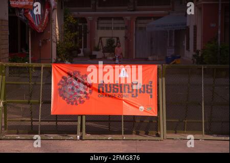 Phnom Penh, Cambogia. 9 maggio 2021. Dopo 3 settimane di chiusura totale della città, il governo ha diviso Phnom Penh in 3 zone colorate (rosso, arancione e giallo) a causa dell'aumento di COVID in corso. Un checkpoint della polizia, con un grande banner bilingue colorato, all'ingresso di una "zona arancione", Credito: Kraig Lieb / Alamy Live News Foto Stock