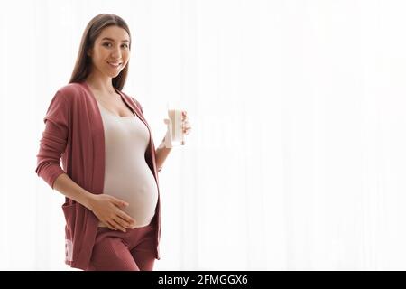 Bevande sane durante la gravidanza. Smiling giovane donna incinta tenendo vetro con latte Foto Stock