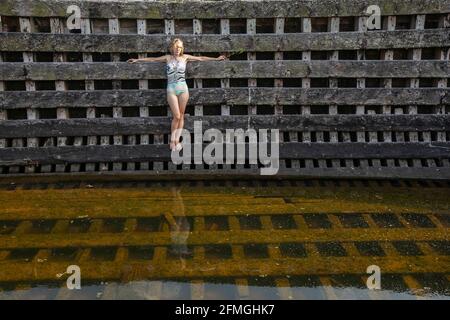 Una giovane donna in costume da bagno si trova a bordo di una barca di legno abbandonata. Foto Stock