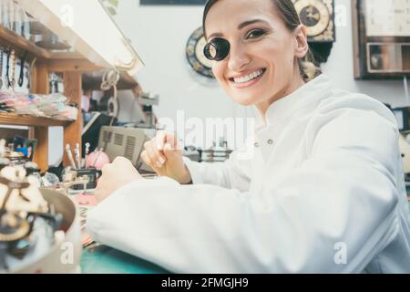 Donna orologiera che guarda la macchina fotografica nella sua officina Foto Stock