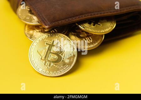 Monete di Bitcoin nel portafoglio su sfondo giallo. Foto Stock