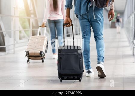 Persone diverse a piedi nel terminal dell'aeroporto con valigia valigia, immagine ritagliata Foto Stock