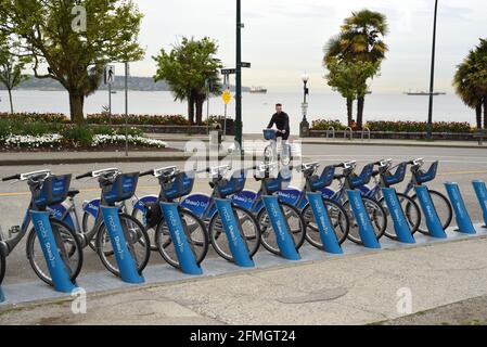 Un uomo restituisce una bicicletta condivisa Mobi Shaw Go a uno stand ufficiale nel West End di Vancouver, British Columbia, Canada Foto Stock