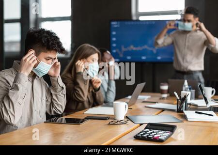 Persone internazionali che indossano maschere mediche sul lavoro Foto Stock