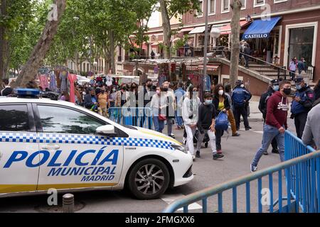 MADRID, SPAGNA - 09 MAGGIO 2021: Auto di polizia alle porte di un mercato di strada a Madrid con una folla di persone dopo la fine dello stato di allarme revocato il 9 maggio, Foto Stock