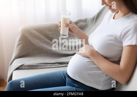 Cropped Shot di incinta donna che tiene vetro con latte e. Pancino a contatto Foto Stock