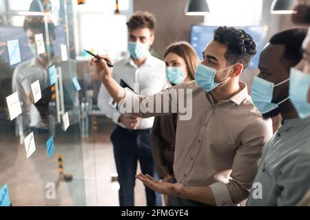 Uomini d'affari che hanno una riunione usando note appiccicose sulla parete di vetro Foto Stock