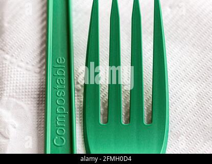 Un macro shot di una forchetta e coltello verdi e compostabili su un tovagliolo bianco crea un design astratto e suggerisce la sostenibilità nella ristorazione e nello stile di vita. Foto Stock