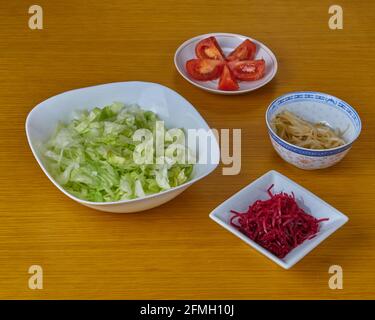 Ingredienti per la preparazione di insalata vegana verde su sfondo di legno. Foto Stock