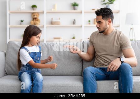 Conflitto di famiglia. Arrabbiato padre nero scolding figlia triste Foto Stock