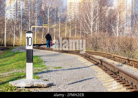 Una tortuosa ferrovia a scartamento ridotto lungo la quale un uomo sta camminando verso edifici residenziali Foto Stock