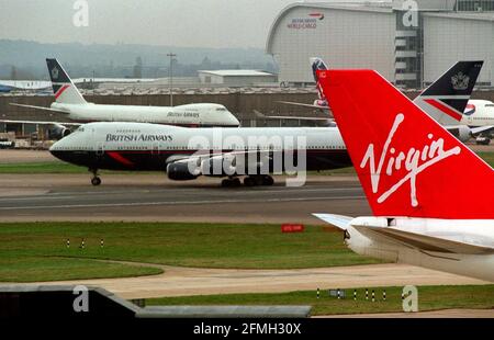 Aeroporto di Heathrow. British Airways Boeing 747 jumbo novembre 1999 atterra a Heathrow e il taxi passa la coda di una Virgin Atlantic Airways 747. Foto Stock
