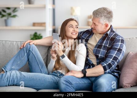 Coppia matura allegra che usa il moderno telefono cellulare a casa Foto Stock