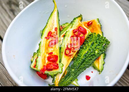 Closeup macro di melone rosso amaro semi vegetali rivestimento che ha un sapore e un aspetto simile ai peperoni rossi tostati nel recipiente Foto Stock