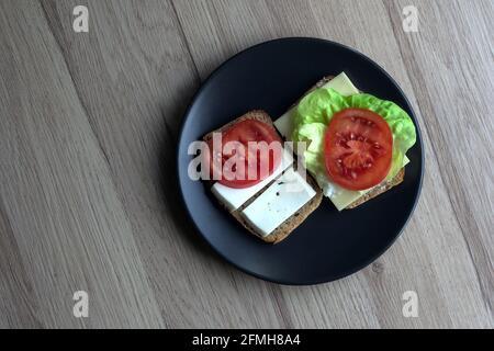 due gustosi panini con formaggio, insalata e pomodoro su un piatto Foto Stock