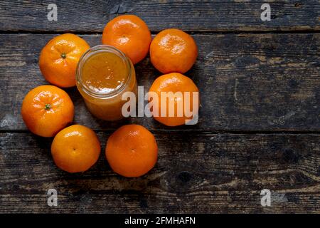 vaso di marmellata circondato da frutti d'arancia su un legno sfondo Foto Stock