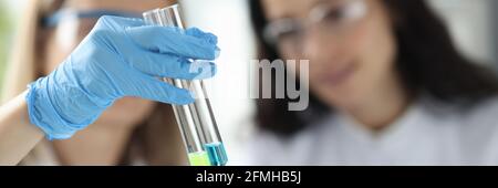 Donne scienziati che tengono provette con liquido in laboratorio Foto Stock