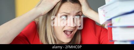 Donna che tiene la testa di fronte a molte cartelle di carta Foto Stock