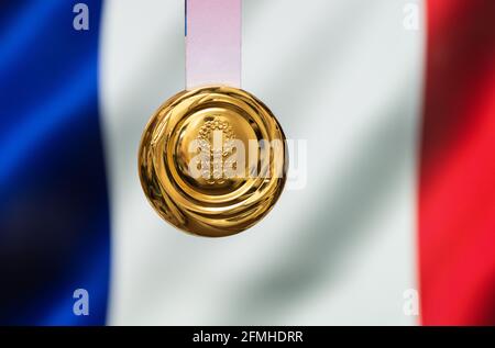 25 aprile 2021 Tokyo, Giappone. Medaglia d'oro dei XXXII Giochi Olimpici estivi 2020 a Tokyo sullo sfondo della bandiera della Francia. Foto Stock
