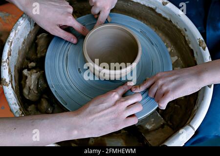 Tagliare una ciotola di ceramica finita con un filo. Artigianato di ceramica tradizionale. Concetto di laboratorio di ceramica Foto Stock