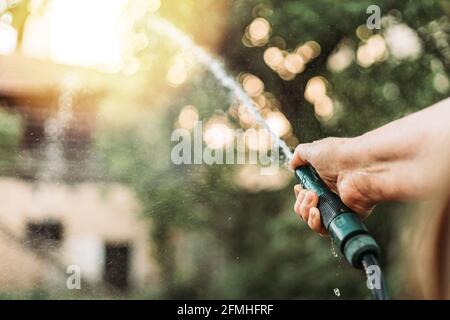 Femmina mano che tiene il tubo di giardinaggio, annaffiatura giardino Foto Stock