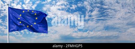 Bandiera dell'Unione europea che sventolava nel vento sul flagpole contro il cielo con nuvole in giornata di sole, bandiera, primo piano Foto Stock