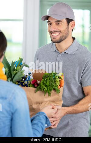 uomo che fa la consegna domestica di scatola vegetale organica Foto Stock