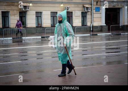 Tambov, Russia. 09 maggio 2021. Una donna anziana in un impermeabile e una maschera facciale cammina lungo la via Sovetskaya durante la Victory Parade. La parata del giorno della vittoria a Tambov (Russia) si è tenuta senza spettatori e veterani della seconda guerra mondiale (Grande Guerra Patriottica) a causa della pandemia del coronavirus. Credit: SOPA Images Limited/Alamy Live News Foto Stock