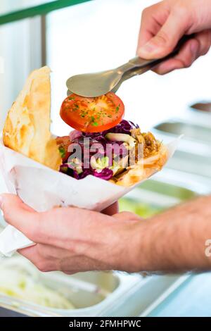 Döner Kebab - gentile venditore in un bagno turco di fast food eatery, con una fresca fatta pane pita o kebab Foto Stock