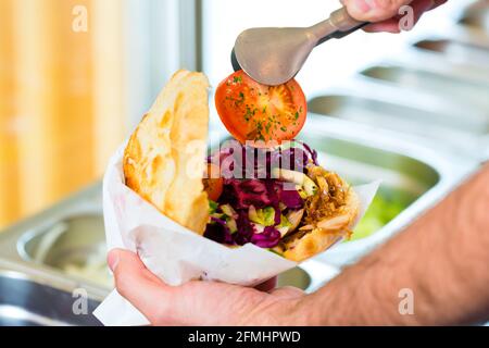 Döner Kebab - gentile venditore in un bagno turco di fast food eatery, con una fresca fatta pane pita o kebab Foto Stock