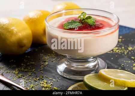 Mousse al limone in una ciotola di cristallo con aggiunta di gelatina di fragola e menta. Foto Stock