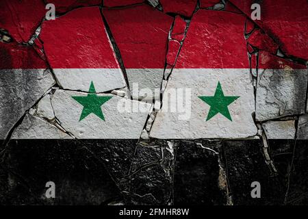 Bandiera nazionale della Siria raffigurante in colori pittorici su un vecchio muro di pietra. Bandiera su sfondo muro rotto. Foto Stock