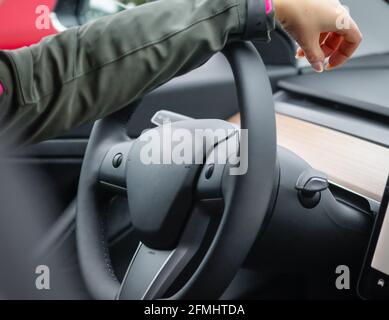 Mano della donna sul volante di un'auto elettrica. Cruscotto auto elettrica. Foto Stock