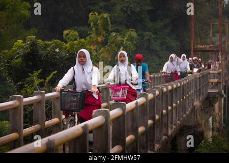 Yogyakarta, Indonesia. 23 agosto 2020. Gli studenti delle scuole elementari in Indonesia vanno a scuola in bicicletta su un ponte Foto Stock