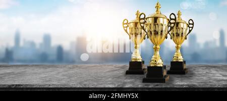 premio 1° campione, il miglior premio e concetto vincitore, coppa del campionato o trofeo vincitore su tavolo di legno con sfondo blu chiaro e bokeh città Foto Stock
