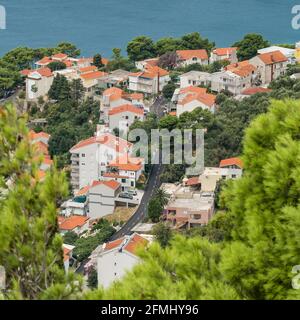 Vista dall'alto sulla strada costiera lungo gli edifici residenziali in Croazia Foto Stock