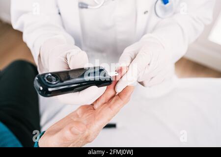 Alto angolo di raccolto anonimo medic che prende il test del sangue di paziente con dispositivo medico in clinica Foto Stock