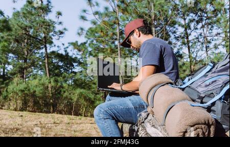 Da sotto nomade seduta su pietra vicino a oggetti personali e l'uso netbook mentre si lavora in remoto Foto Stock