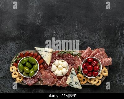 Salumi o antipasti italiani di formaggi assortiti, carni e antipasti. Sopra il tavolo scenografico su un piatto rustico in legno. Spazio per la copia. Foto Stock