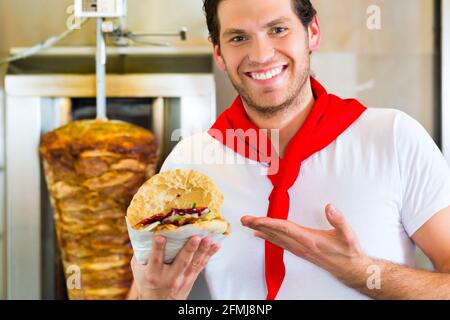 Döner Kebab - gentile venditore in un bagno turco di fast food eatery, con una fresca fatta pane pita o kebab Foto Stock