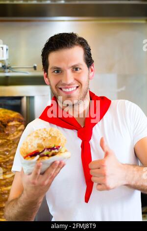 Döner Kebab - gentile venditore in un bagno turco di fast food eatery, con una fresca fatta pane pita o kebab Foto Stock