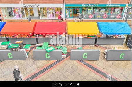 Bancarelle al mercato coperto di fronte ai negozi di Bonmarche e Poundland nel centro commerciale di Corby, Northamptonshire, Inghilterra. Foto Stock