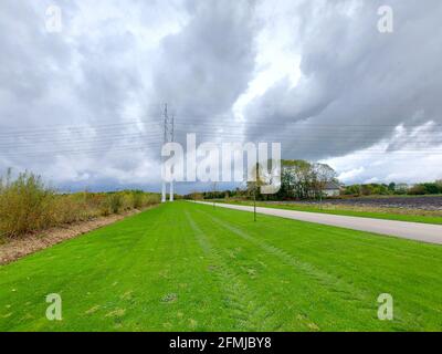Nubi di cumulo scuro sopra l'erba verde e le linee di alimentazione della pista di avvizzamento Nella zona ricreativa di Bentwoud Foto Stock