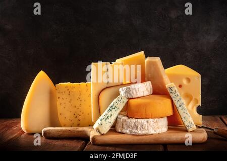 Varietà di formaggio su sfondi rustici scuri. Formaggi morbidi e duri, vista laterale con un posto per il testo Foto Stock