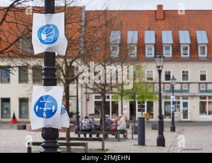 07 maggio 2021, Brandeburgo, Wittstock/Dosse: Fogli sminuzzati con immagini stilizzate su un lampione nella piazza di fronte al municipio ricordano ai passanti l'obbligo di indossare una maschera e di mantenere la distanza sulla piazza del mercato. Foto: Soeren Stache/dpa-Zentralbild/ZB Foto Stock