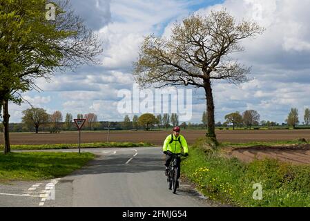 Uomo in bicicletta su strada di campagna nel Nord Yorkshire, Inghilterra Regno Unito Foto Stock