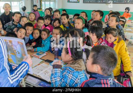 Gli studenti della scuola elementare Lixiana nelle zone rurali di Hebei, in Cina, hanno letto a voce alta la storia di Natale. Foto Stock