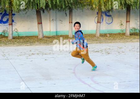 Gli studenti della scuola lixiana nelle zone rurali di Hebei, in Cina, scappare durante il gioco cattura la bandiera. Foto Stock