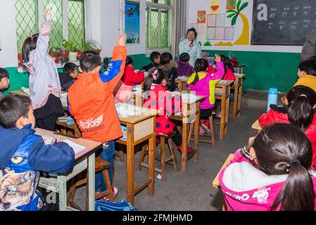 Gli studenti alzano le mani per rispondere alla domanda dell'insegnante durante una lezione cinese. Foto Stock