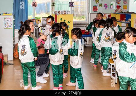 L'insegnante alla scuola di Boai aiuta gli studenti con loro progetto artigianale Foto Stock